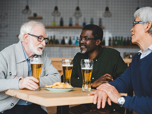 Guys enjoying beers and conversation at local brewery.>